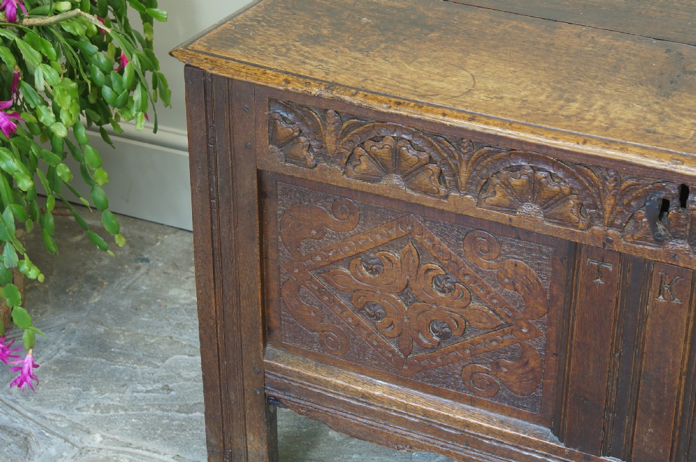 A small 17th-century dark oak coffer featuring hand-carved diamond panels, a decorative top frieze, and pegged joinery. View X
