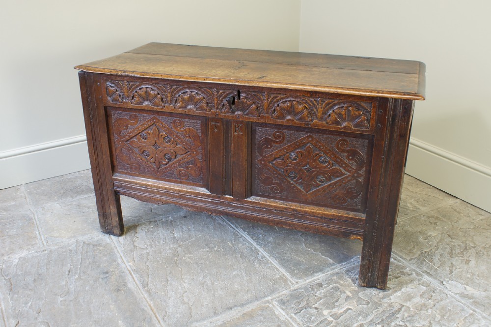 A small 17th-century dark oak coffer featuring hand-carved diamond panels, a decorative top frieze, and pegged joinery. View XIII