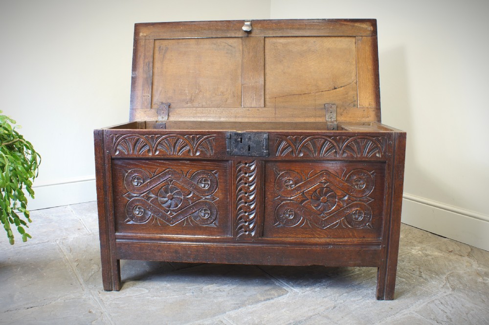 A 17th-century dark oak coffer featuring two carved front panels with geometric rosettes, an arcaded top rail, and an iron lockplate. View II