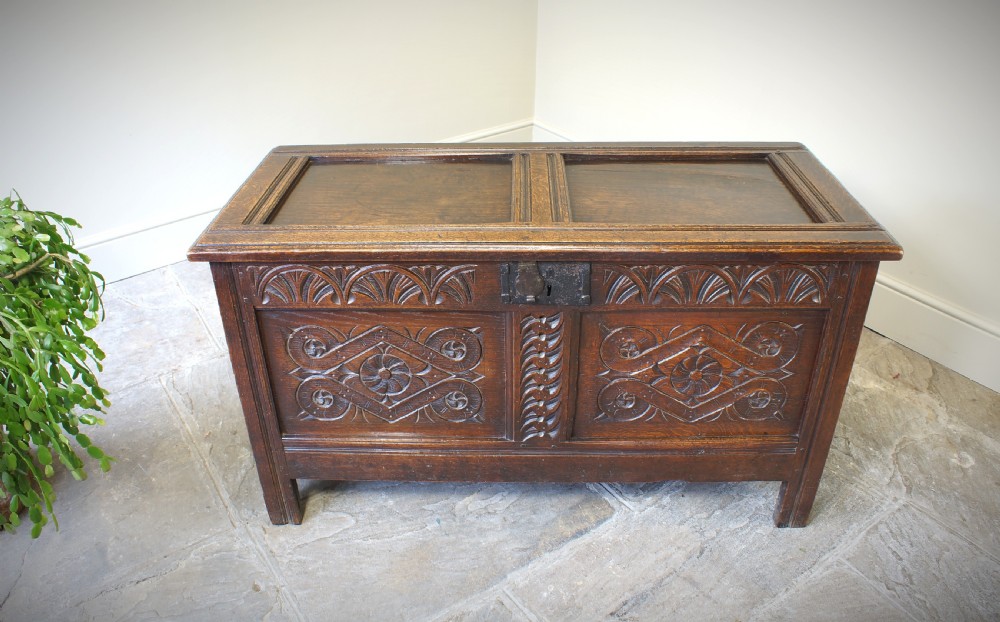 A 17th-century dark oak coffer featuring two carved front panels with geometric rosettes, an arcaded top rail, and an iron lockplate. View III
