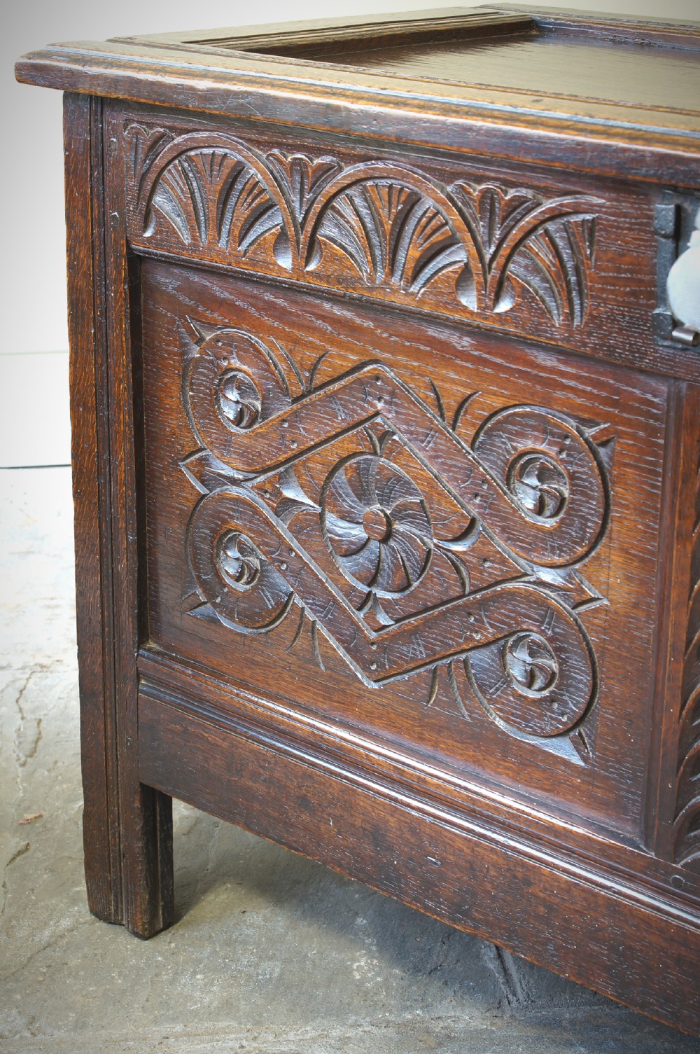 A 17th-century dark oak coffer featuring two carved front panels with geometric rosettes, an arcaded top rail, and an iron lockplate. View VII