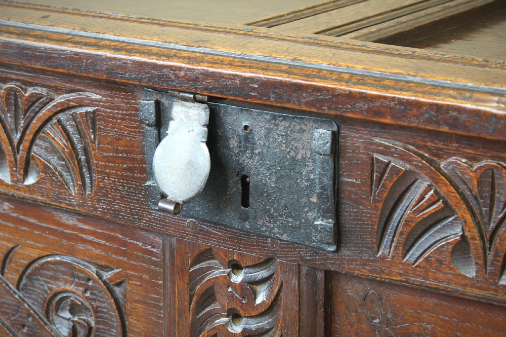 A 17th-century dark oak coffer featuring two carved front panels with geometric rosettes, an arcaded top rail, and an iron lockplate. View IX
