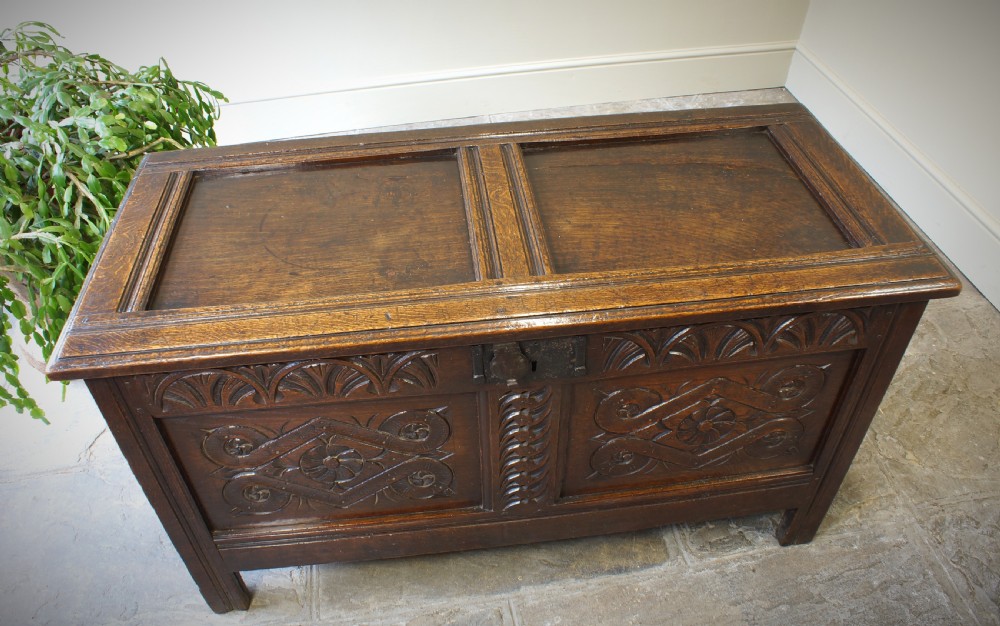 A 17th-century dark oak coffer featuring two carved front panels with geometric rosettes, an arcaded top rail, and an iron lockplate. View XI