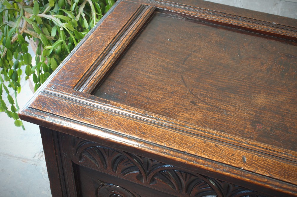 A 17th-century dark oak coffer featuring two carved front panels with geometric rosettes, an arcaded top rail, and an iron lockplate. View XII