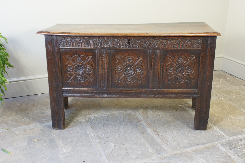 A small 17th-century dark oak coffer featuring three carved front panels, a carved top rail, and a hinged rectangular lid. View III