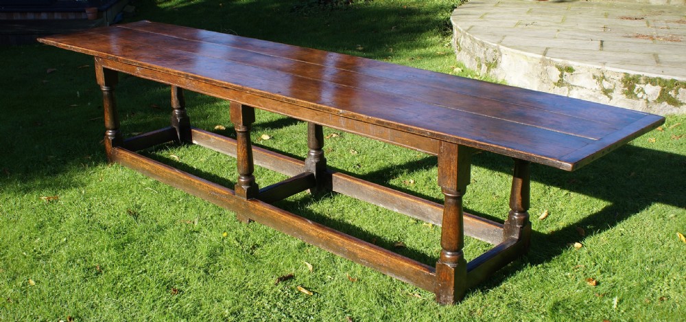A large 17th-century oak refectory dining table with a long plank top, six turned legs, and robust perimeter stretchers.