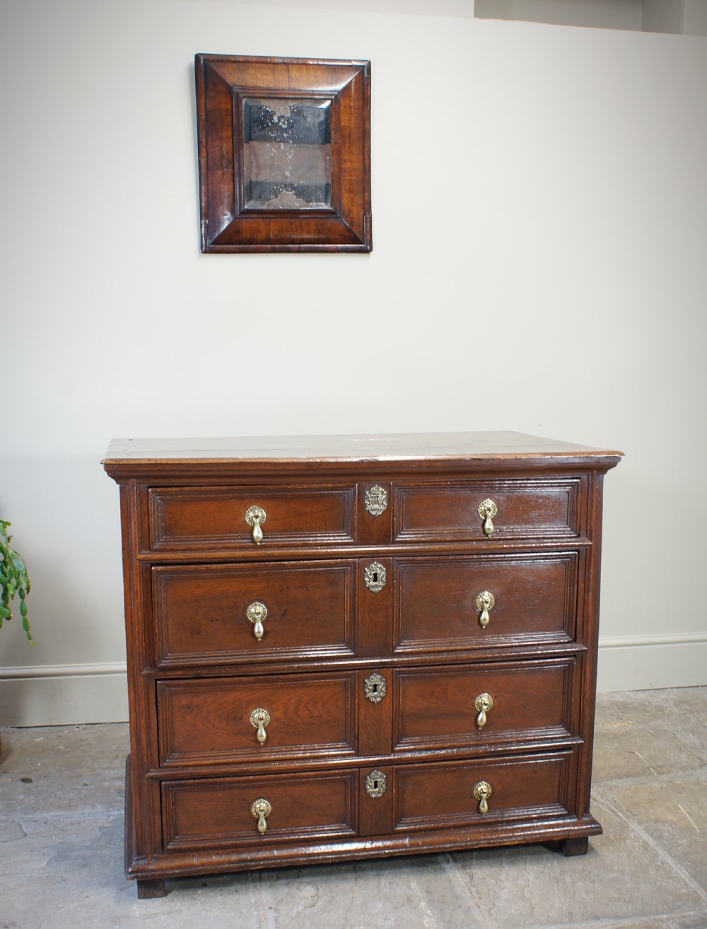 A seventeenth-century dark oak chest of drawers featuring geometric applied mouldings and brass teardrop handles. View II