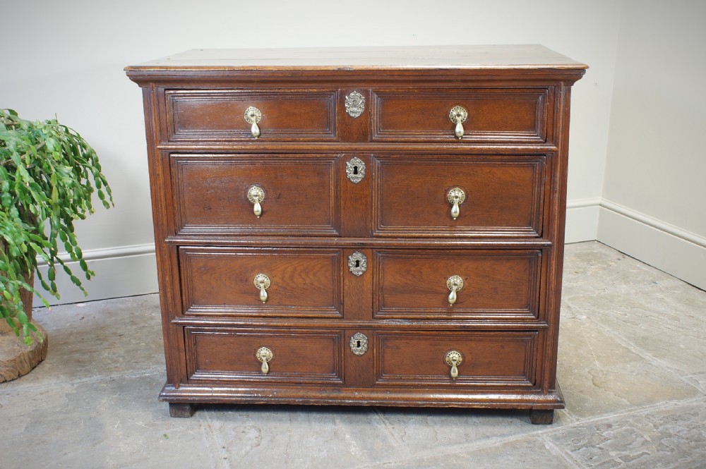 A seventeenth-century dark oak chest of drawers featuring geometric applied mouldings and brass teardrop handles. View V