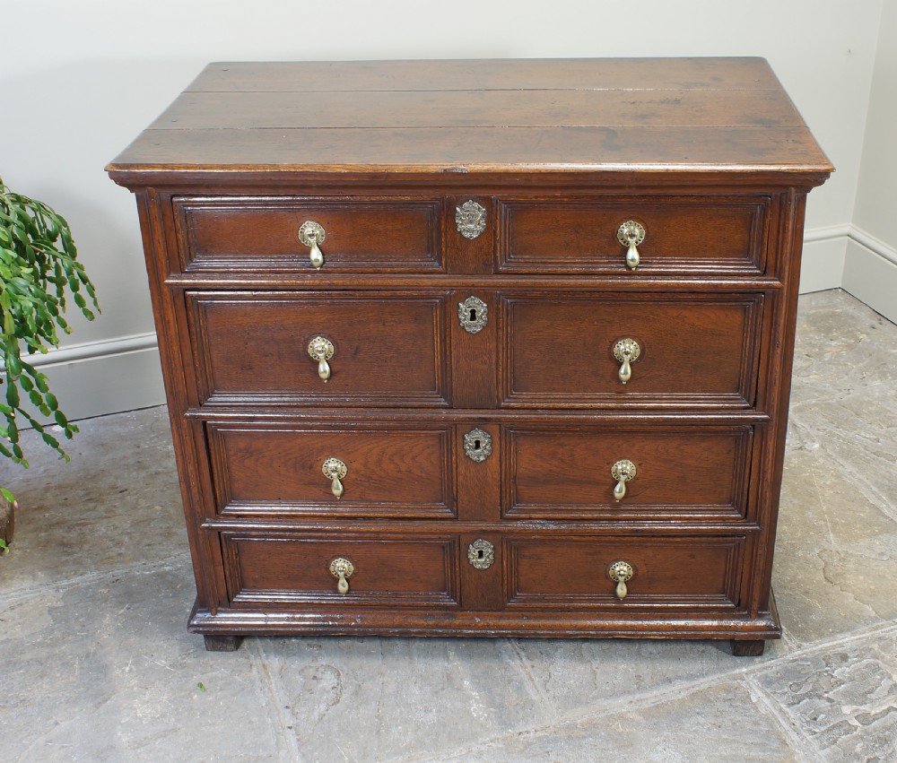 A seventeenth-century dark oak chest of drawers featuring geometric applied mouldings and brass teardrop handles. View VI