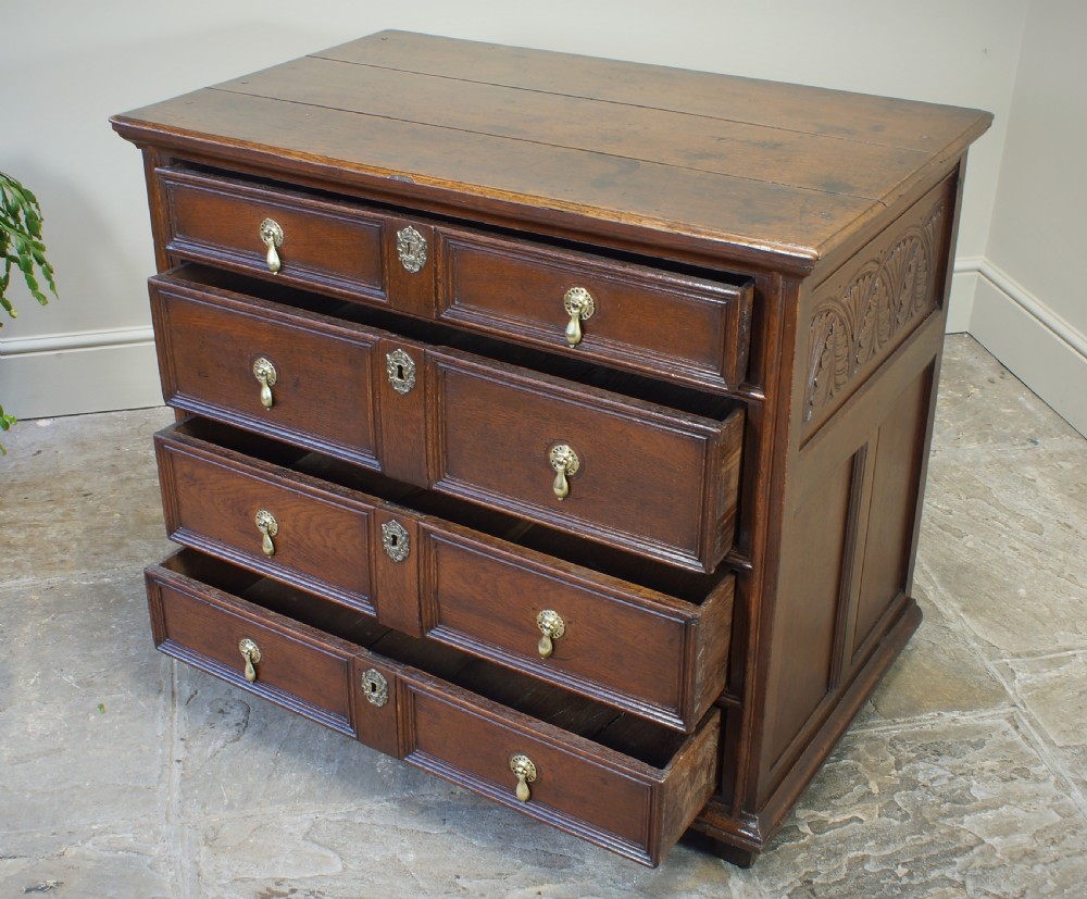 A seventeenth-century dark oak chest of drawers featuring geometric applied mouldings and brass teardrop handles. View VII
