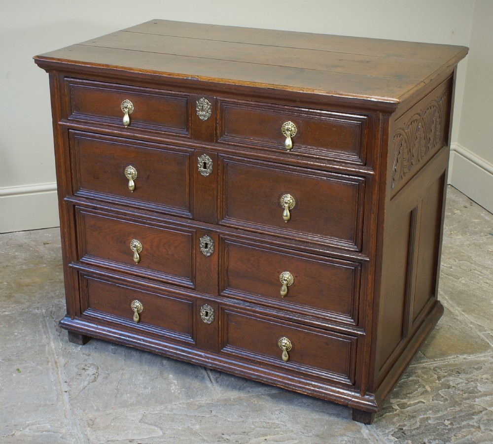 A seventeenth-century dark oak chest of drawers featuring geometric applied mouldings and brass teardrop handles. View VIII