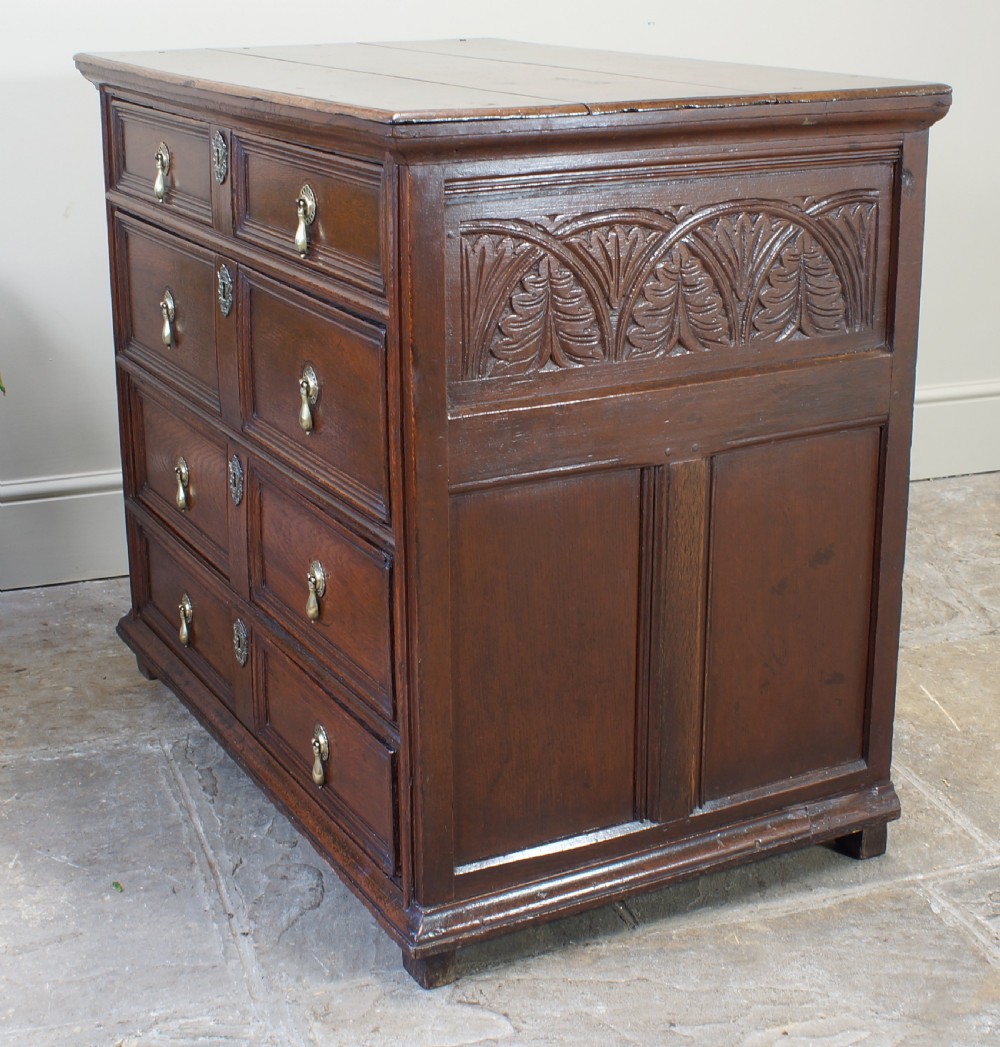 A seventeenth-century dark oak chest of drawers featuring geometric applied mouldings and brass teardrop handles. View IX