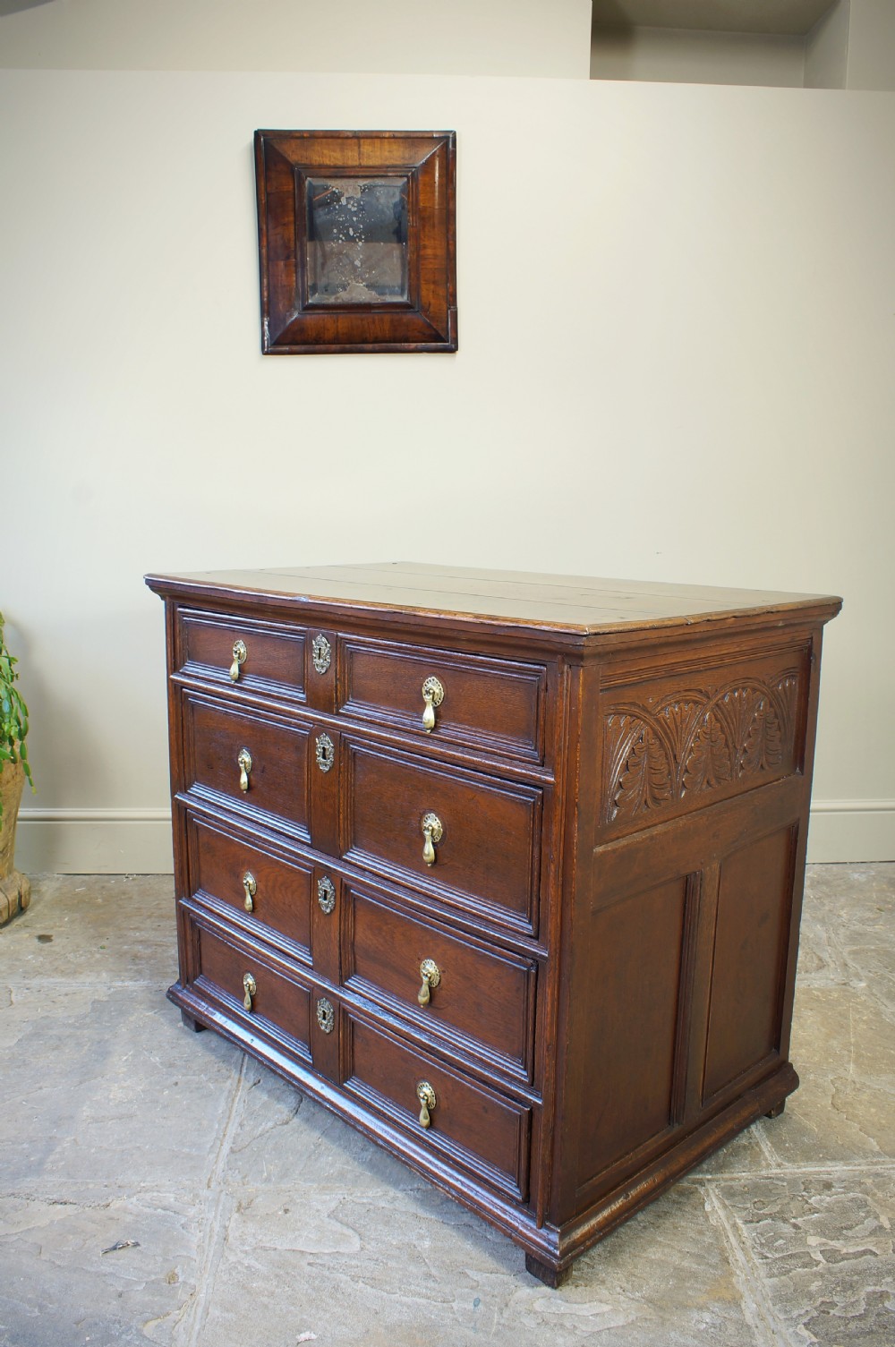 A seventeenth-century dark oak chest of drawers featuring geometric applied mouldings and brass teardrop handles. View X