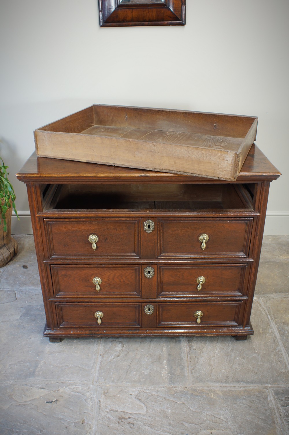 A seventeenth-century dark oak chest of drawers featuring geometric applied mouldings and brass teardrop handles. View XIV