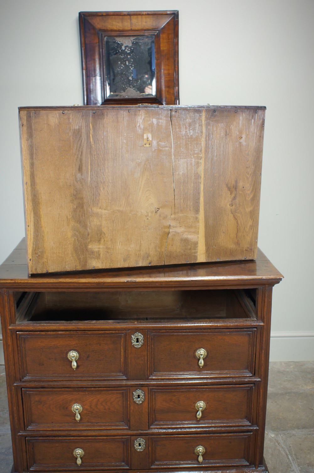A seventeenth-century dark oak chest of drawers featuring geometric applied mouldings and brass teardrop handles. View XVI