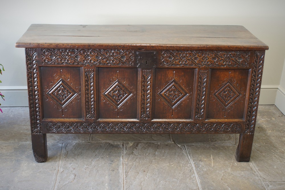 A 17th-century carved dark oak coffer with four front panels featuring diamond motifs, a carved frieze, and a flat hinged lid. View III