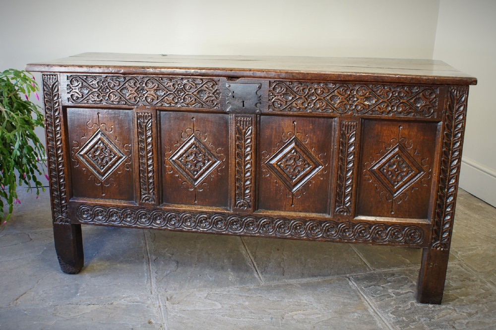 A 17th-century carved dark oak coffer with four front panels featuring diamond motifs, a carved frieze, and a flat hinged lid. View VIII