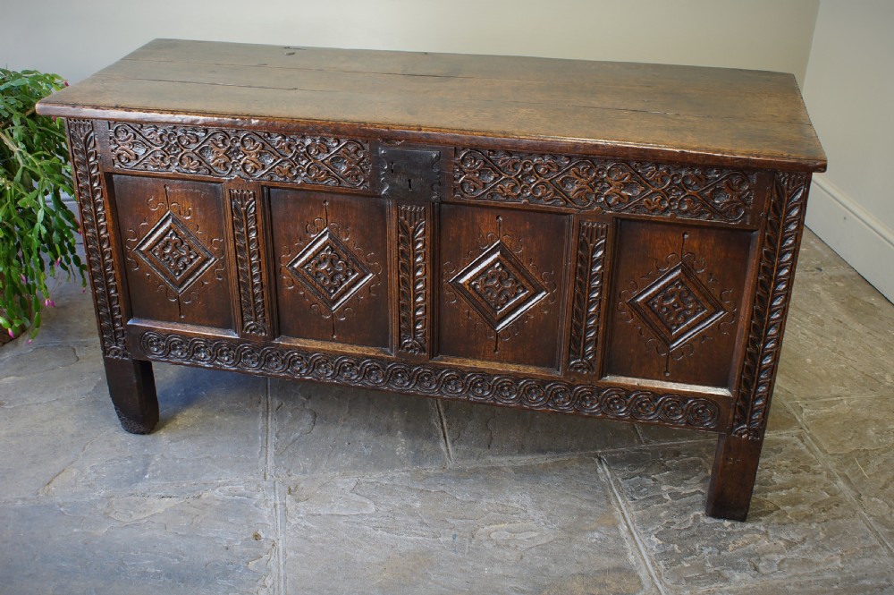 A 17th-century carved dark oak coffer with four front panels featuring diamond motifs, a carved frieze, and a flat hinged lid. View IX