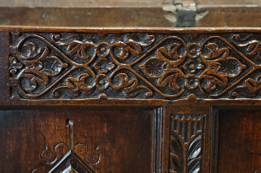 A 17th-century carved dark oak coffer with four front panels featuring diamond motifs, a carved frieze, and a flat hinged lid. View XV