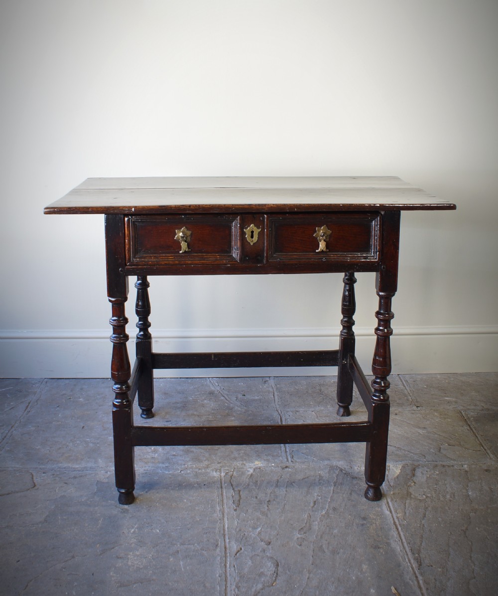 A late 17th-century dark oak side table featuring a single moulded drawer front, brass escutcheon, baluster-turned legs, and a perimeter box stretcher. View II