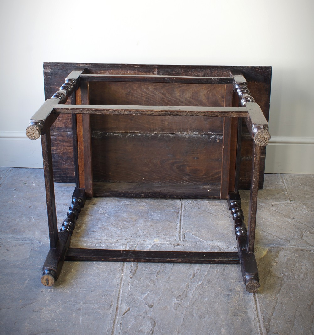 A late 17th-century dark oak side table featuring a single moulded drawer front, brass escutcheon, baluster-turned legs, and a perimeter box stretcher. View VI