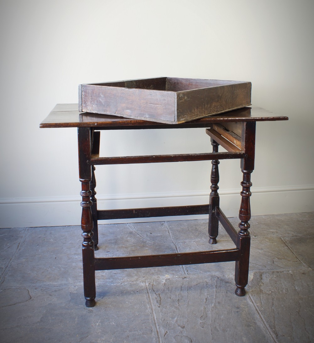 A late 17th-century dark oak side table featuring a single moulded drawer front, brass escutcheon, baluster-turned legs, and a perimeter box stretcher. View XI