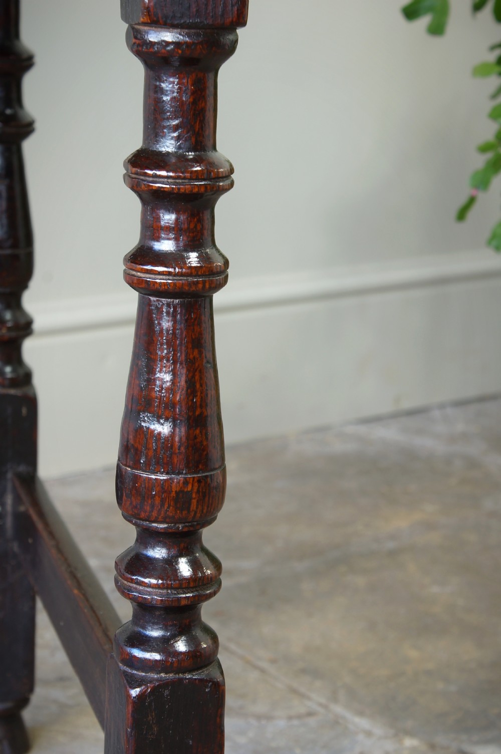A late 17th-century dark oak side table featuring a single moulded drawer front, brass escutcheon, baluster-turned legs, and a perimeter box stretcher. View XVI