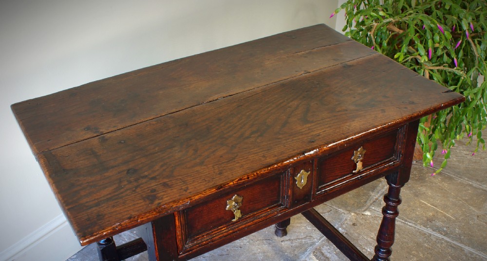 A late 17th-century dark oak side table featuring a single moulded drawer front, brass escutcheon, baluster-turned legs, and a perimeter box stretcher. View XVIII