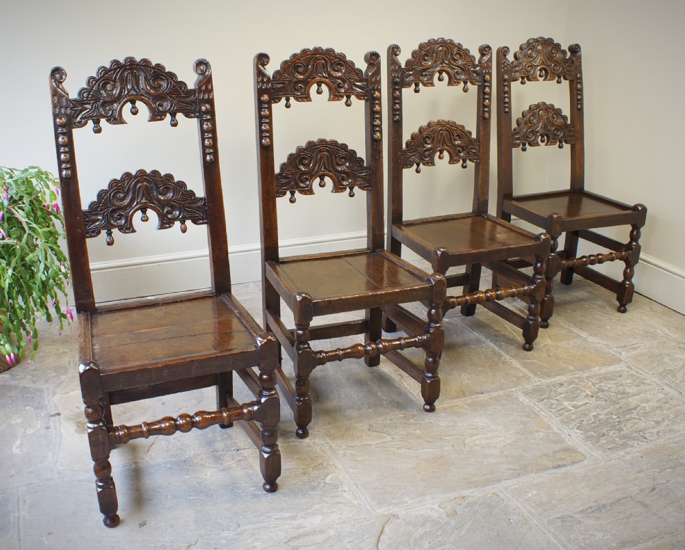 Set of four 17th-century carved dark oak backstool chairs featuring openwork carved cresting rails, turned stretchers, and solid wooden panel seats. View II