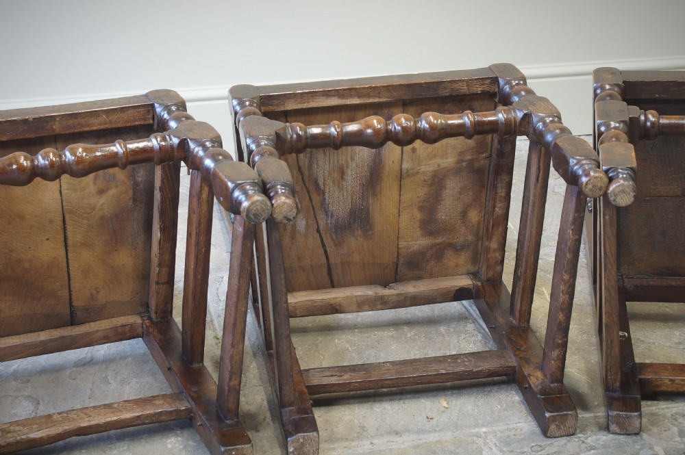 Set of four 17th-century carved dark oak backstool chairs featuring openwork carved cresting rails, turned stretchers, and solid wooden panel seats. View III