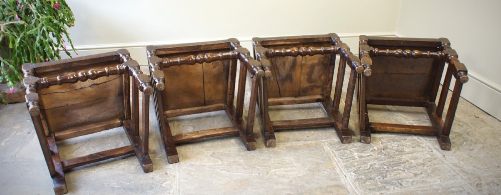 Set of four 17th-century carved dark oak backstool chairs featuring openwork carved cresting rails, turned stretchers, and solid wooden panel seats. View V