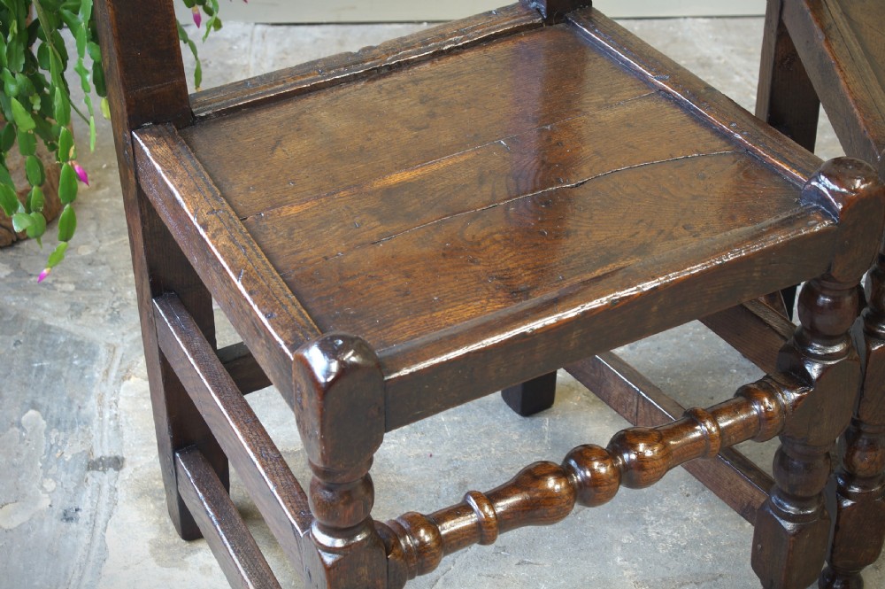 Set of four 17th-century carved dark oak backstool chairs featuring openwork carved cresting rails, turned stretchers, and solid wooden panel seats. View VII