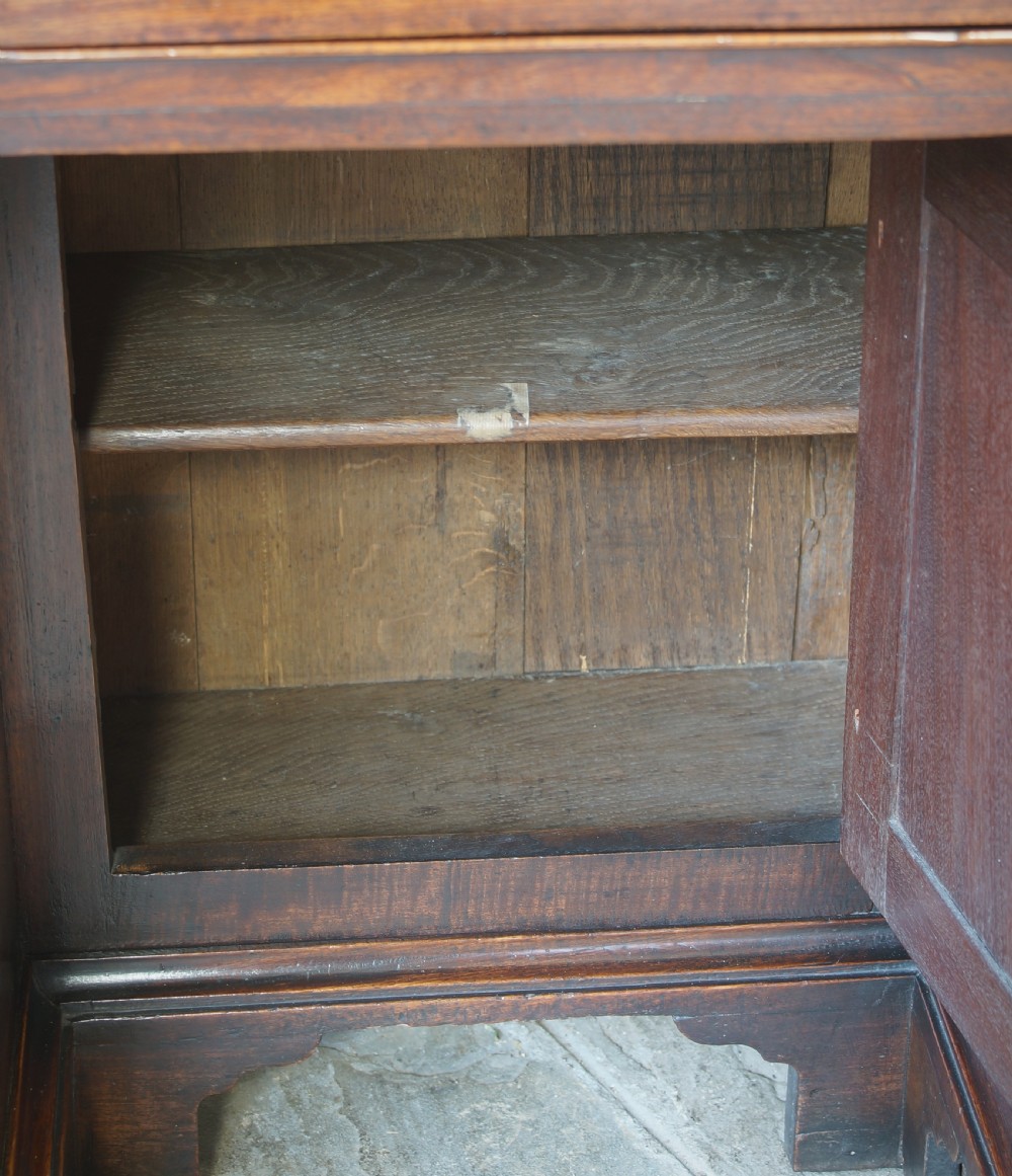 An early Georgian mahogany kneehole bureau featuring a slanted fall-front top lid, brass drop handles, multiple drawers, and a central recessed cupboard on bracket feet. View XVII