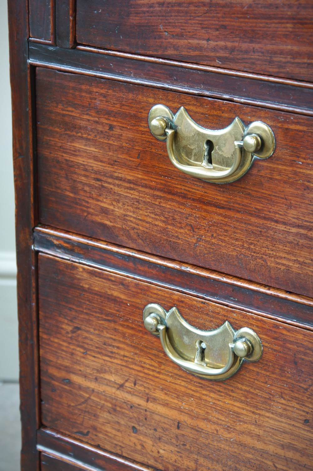 An early Georgian mahogany kneehole bureau featuring a slanted fall-front top lid, brass drop handles, multiple drawers, and a central recessed cupboard on bracket feet. View XIX