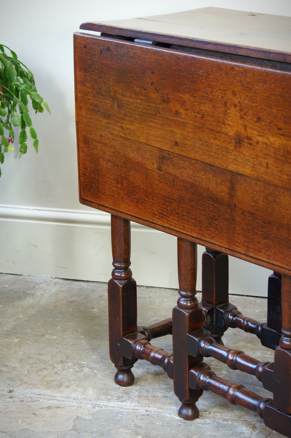 An antique late 17th-century walnut gateleg table featuring turned legs, stretchers, a single frieze drawer, and two hinged drop leaves. View II