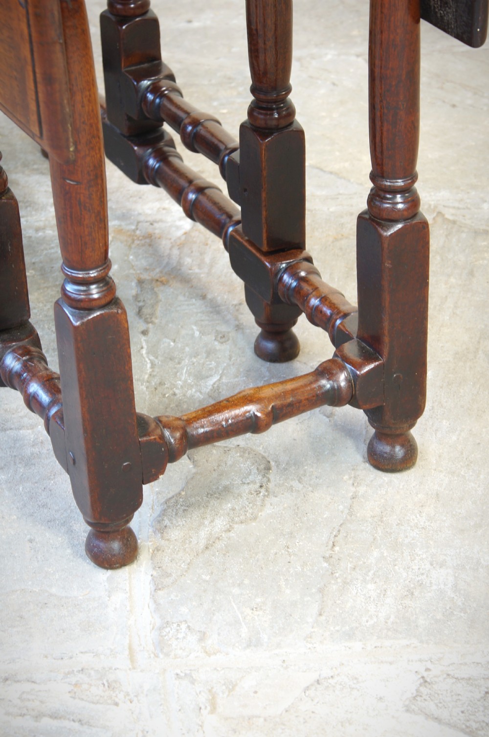 An antique late 17th-century walnut gateleg table featuring turned legs, stretchers, a single frieze drawer, and two hinged drop leaves. View III
