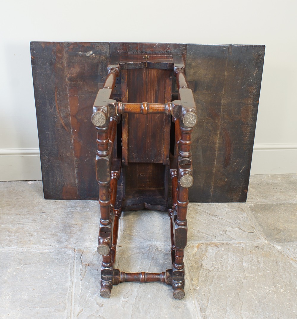 An antique late 17th-century walnut gateleg table featuring turned legs, stretchers, a single frieze drawer, and two hinged drop leaves. View VIII