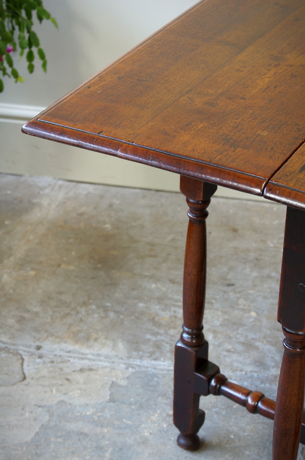 An antique late 17th-century walnut gateleg table featuring turned legs, stretchers, a single frieze drawer, and two hinged drop leaves. View X