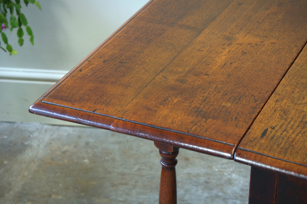 An antique late 17th-century walnut gateleg table featuring turned legs, stretchers, a single frieze drawer, and two hinged drop leaves. View XI