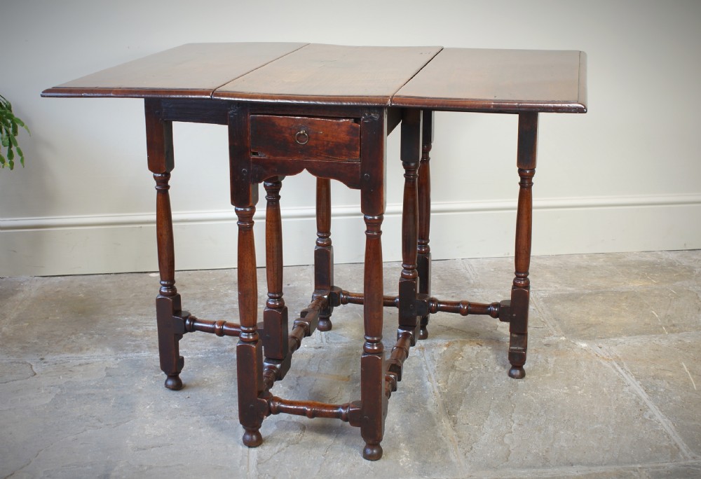 An antique late 17th-century walnut gateleg table featuring turned legs, stretchers, a single frieze drawer, and two hinged drop leaves. View XIII