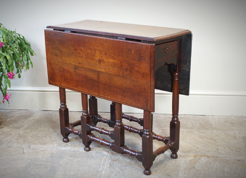An antique late 17th-century walnut gateleg table featuring turned legs, stretchers, a single frieze drawer, and two hinged drop leaves. View XIV