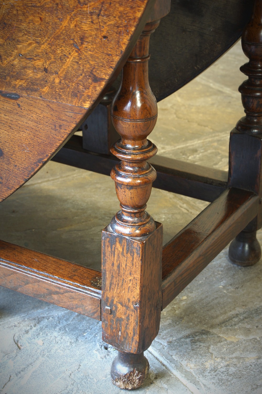 A large 17th-century oak gateleg table featuring an oval drop-leaf top, baluster-turned legs, sturdy box stretchers, and a end drawer. View VIII