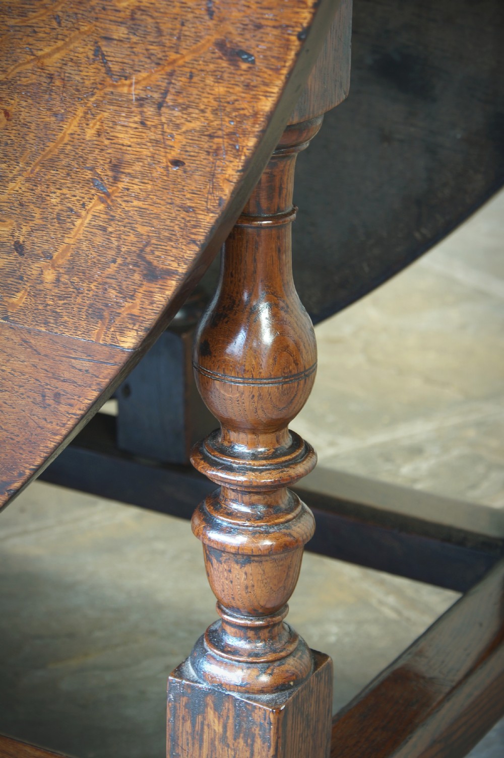 A large 17th-century oak gateleg table featuring an oval drop-leaf top, baluster-turned legs, sturdy box stretchers, and a end drawer. View IX