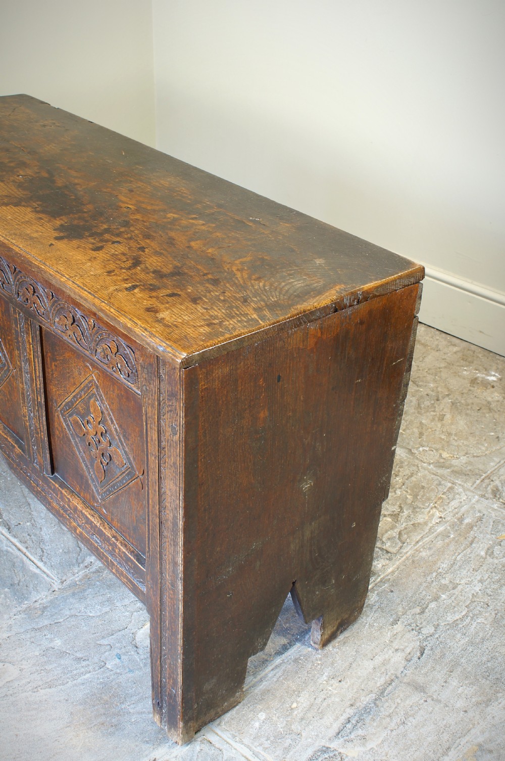 An early 17th-century oak coffer featuring three carved panels with lozenge motifs, an upper carved frieze, and an iron escutcheon. View II