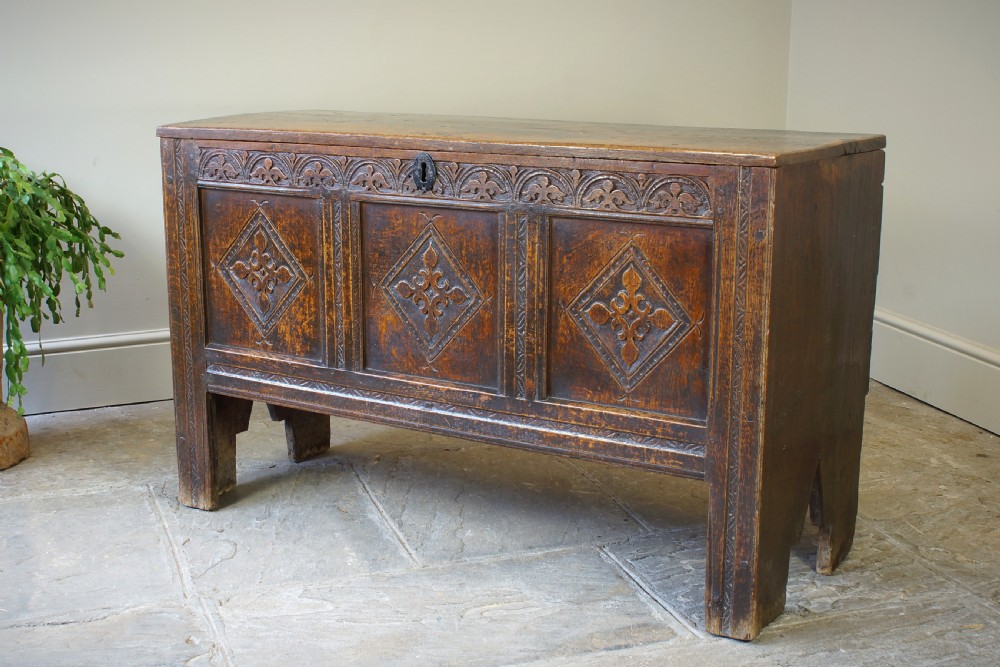 An early 17th-century oak coffer featuring three carved panels with lozenge motifs, an upper carved frieze, and an iron escutcheon. View VII