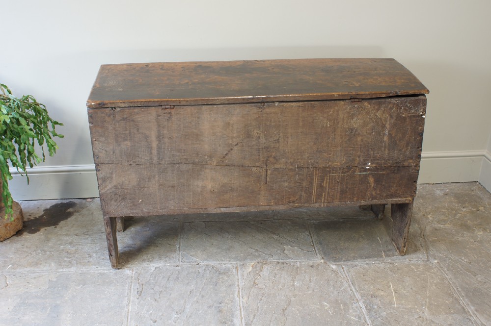 An early 17th-century oak coffer featuring three carved panels with lozenge motifs, an upper carved frieze, and an iron escutcheon. View X