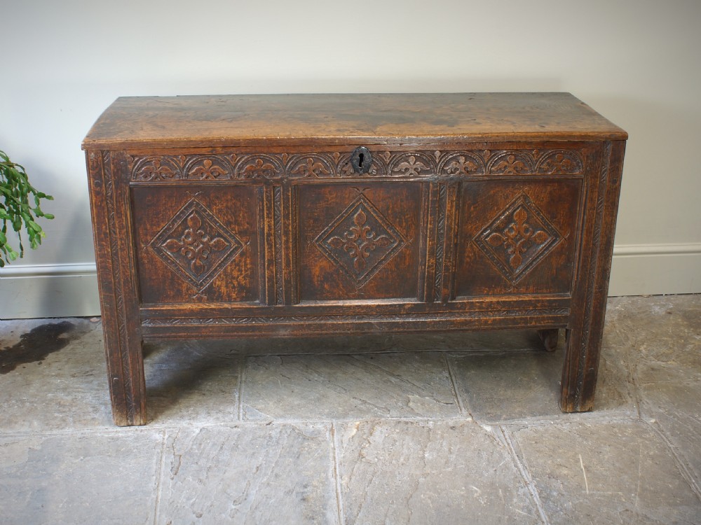 An early 17th-century oak coffer featuring three carved panels with lozenge motifs, an upper carved frieze, and an iron escutcheon. View XI