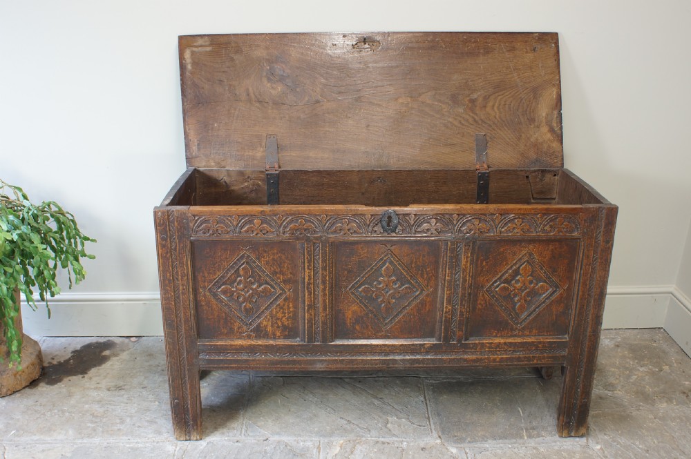 An early 17th-century oak coffer featuring three carved panels with lozenge motifs, an upper carved frieze, and an iron escutcheon. View XIV