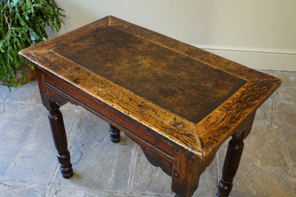 An early 17th century dark oak table with a framed rectangular top, turned legs, and pegged mortise and tenon joinery. View II