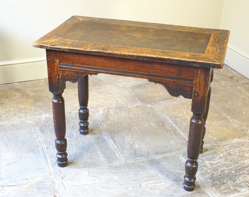 An early 17th century dark oak table with a framed rectangular top, turned legs, and pegged mortise and tenon joinery. View V
